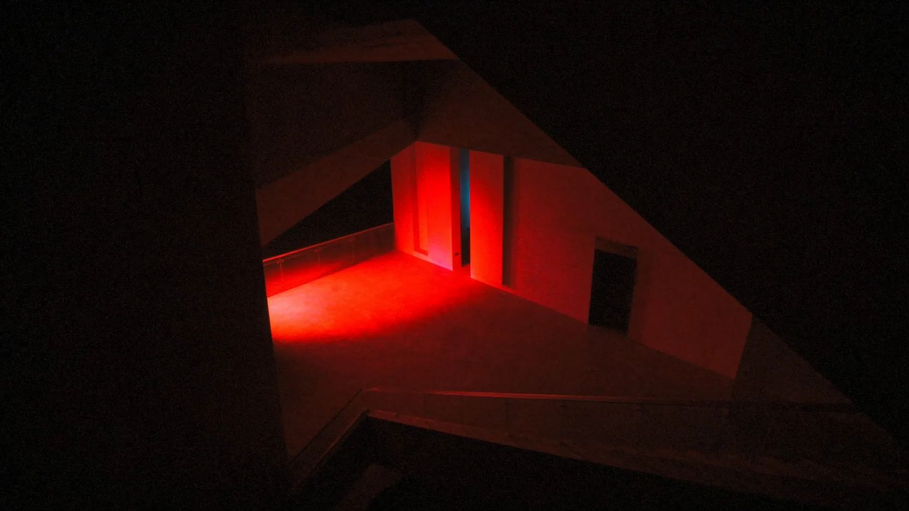 A dark interior lit by a shaft of red light — the studio's visual signature.